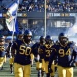 WVU Football team carrying flag