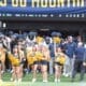 WVU Football team behind cheerleaders