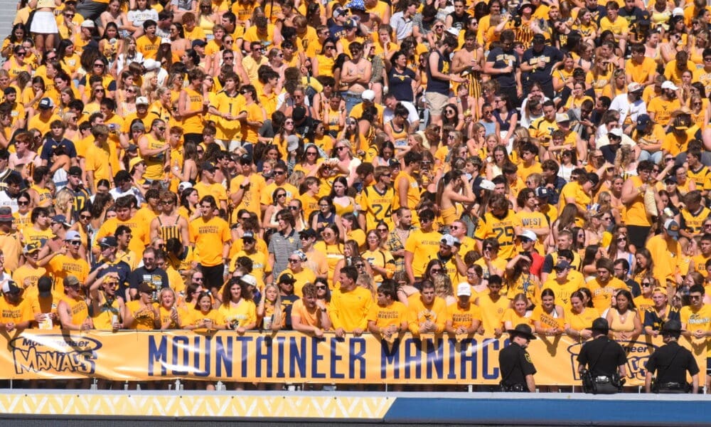 WVU Football fans in student section with Mountaineer Maniacs sign STOCK