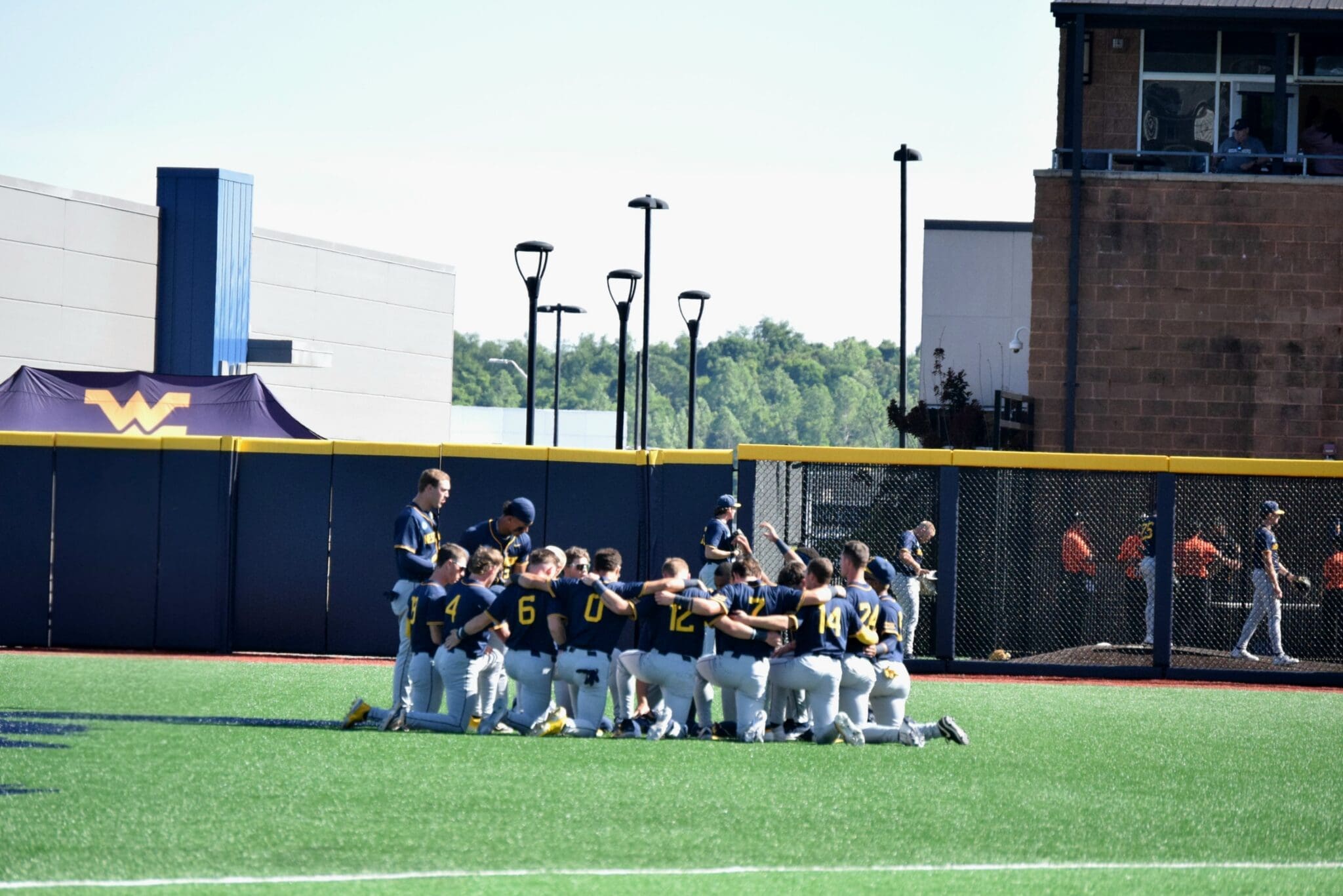 WVU Baseball players huddle on field before Morgantown Regional