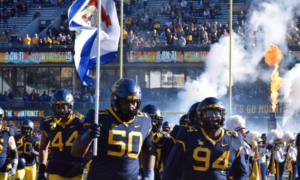 WVU Football players carrying flag