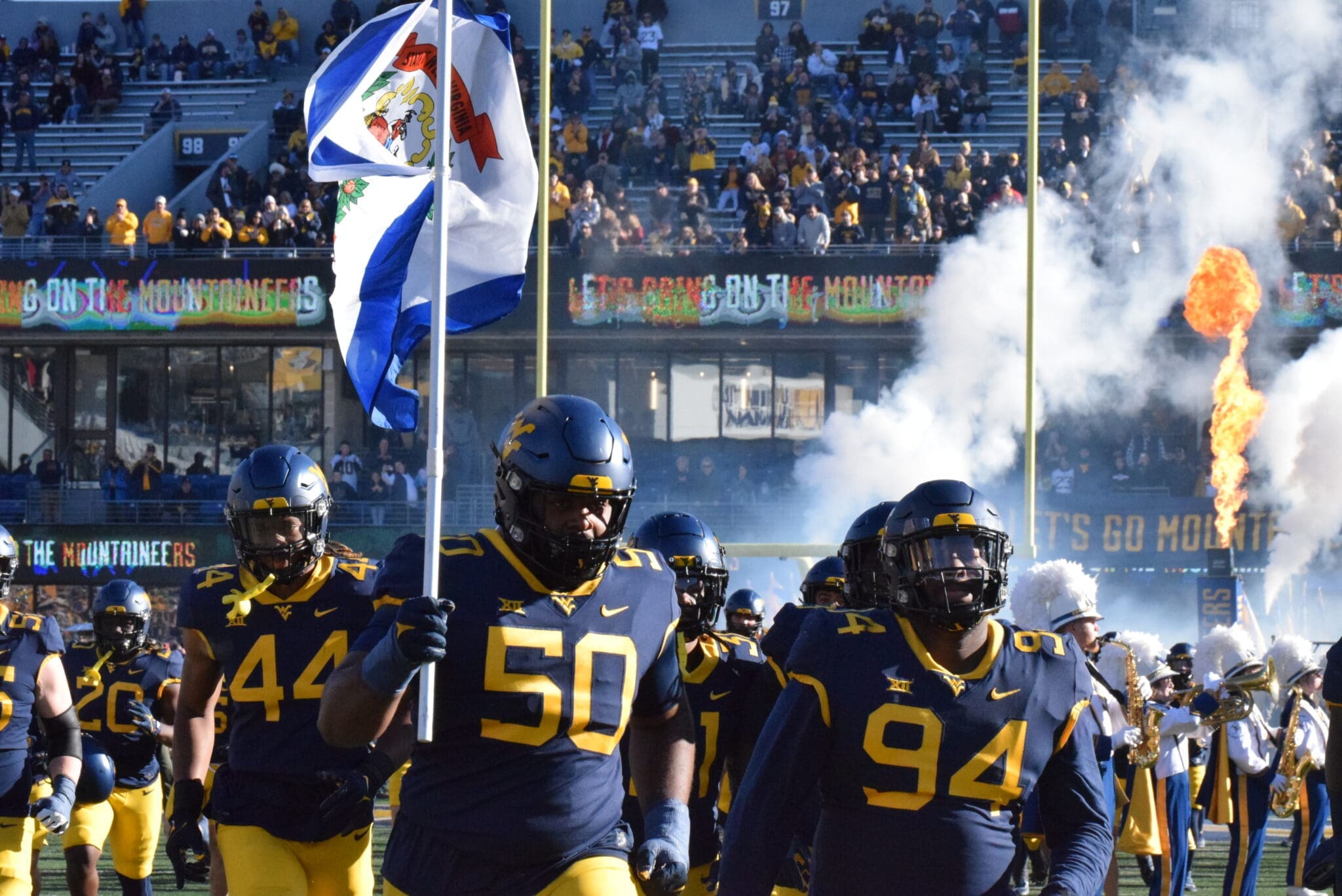 WVU Football players carrying flag