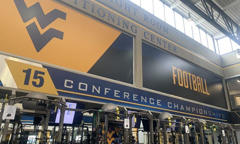 WVU Football conference titles on wall of weight room