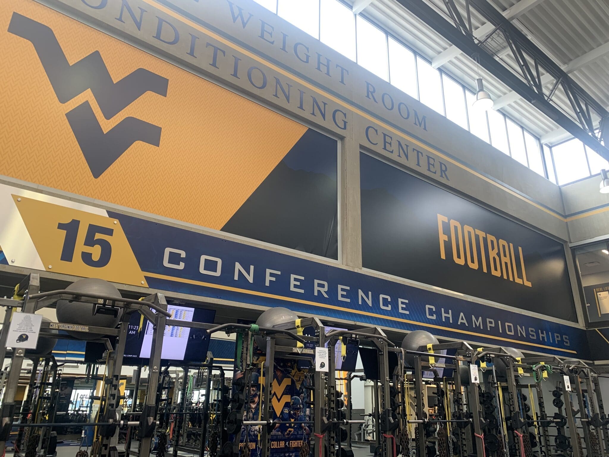 WVU Football conference titles on wall of weight room