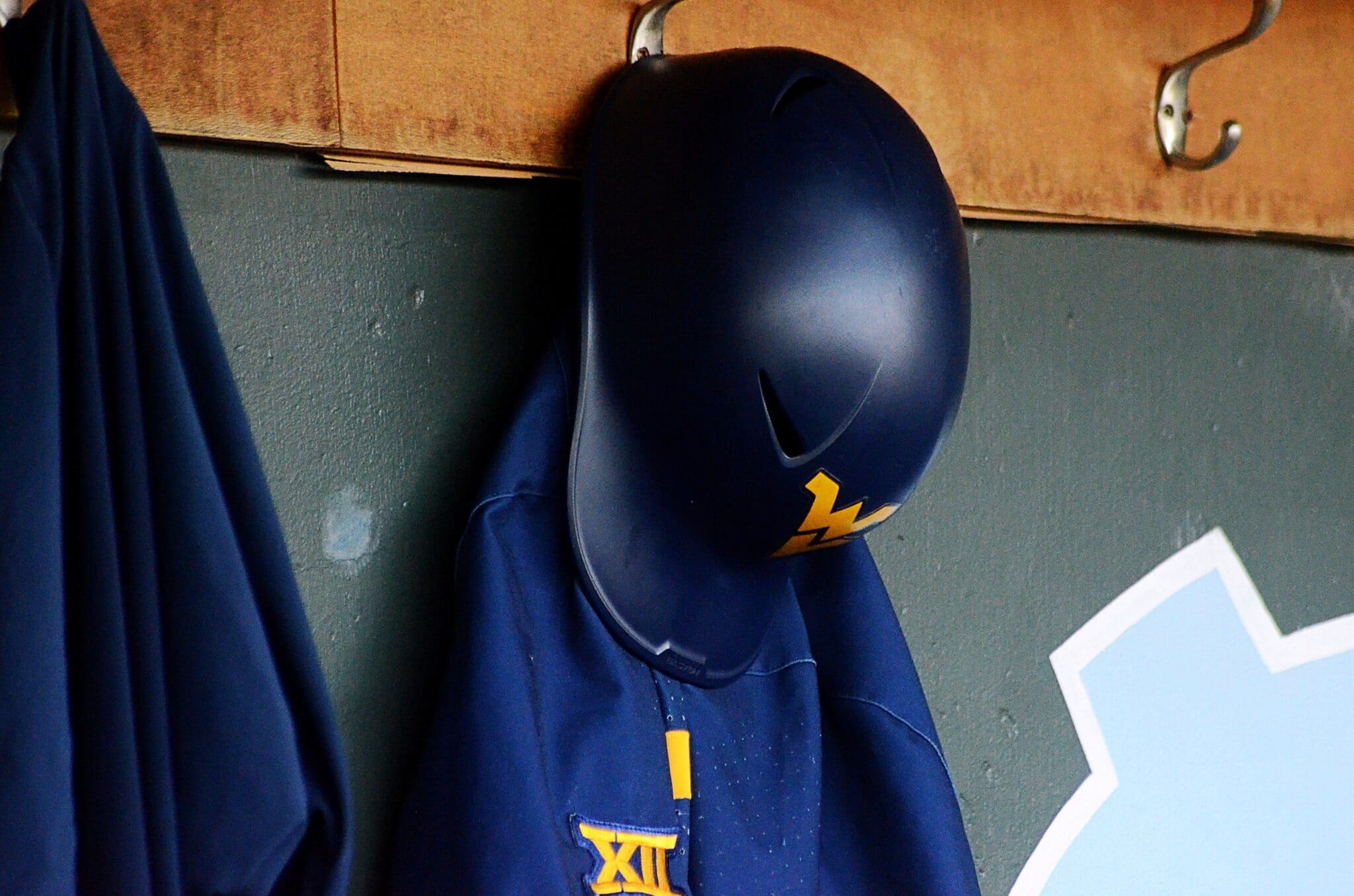 A WVU helmet hangs in the dugout as the Mountaineers played against North Carolina on June 8, 2024, in the Super Regionals of the NCAA Tournament at Boshamer Stadium in Chapel Hill, N.C. (Mitchell Northam / WV Sports Now)