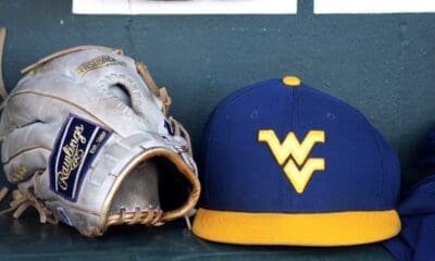 A WVU baseball hat and glove sits in the dugout as the Mountaineers played against North Carolina on June 8, 2024, in the Super Regionals of the NCAA Tournament at Boshamer Stadium in Chapel Hill, N.C. (Mitchell Northam / WV Sports Now)