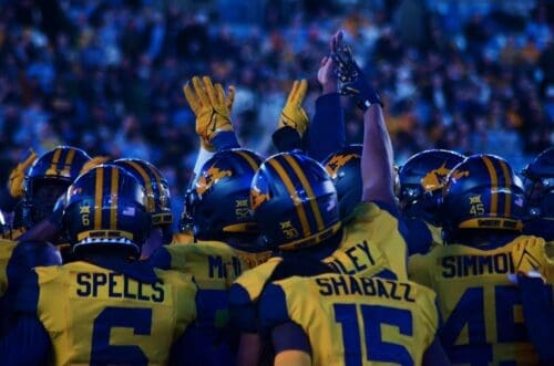 WVU Football players huddle up before the fourth quarter against UNC at the Duke's Mayo Bowl on Dec. 27, 2023, at Bank of America Stadium in Charlotte, N.C. (Mitchell Northam / WV Sports Now)