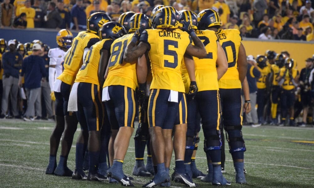 WVU Football Offense huddling with Devin Carter