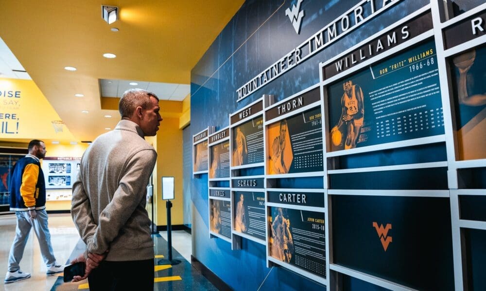 Wren Baker and Ross Hodge Looking at WVU Basketball Wall